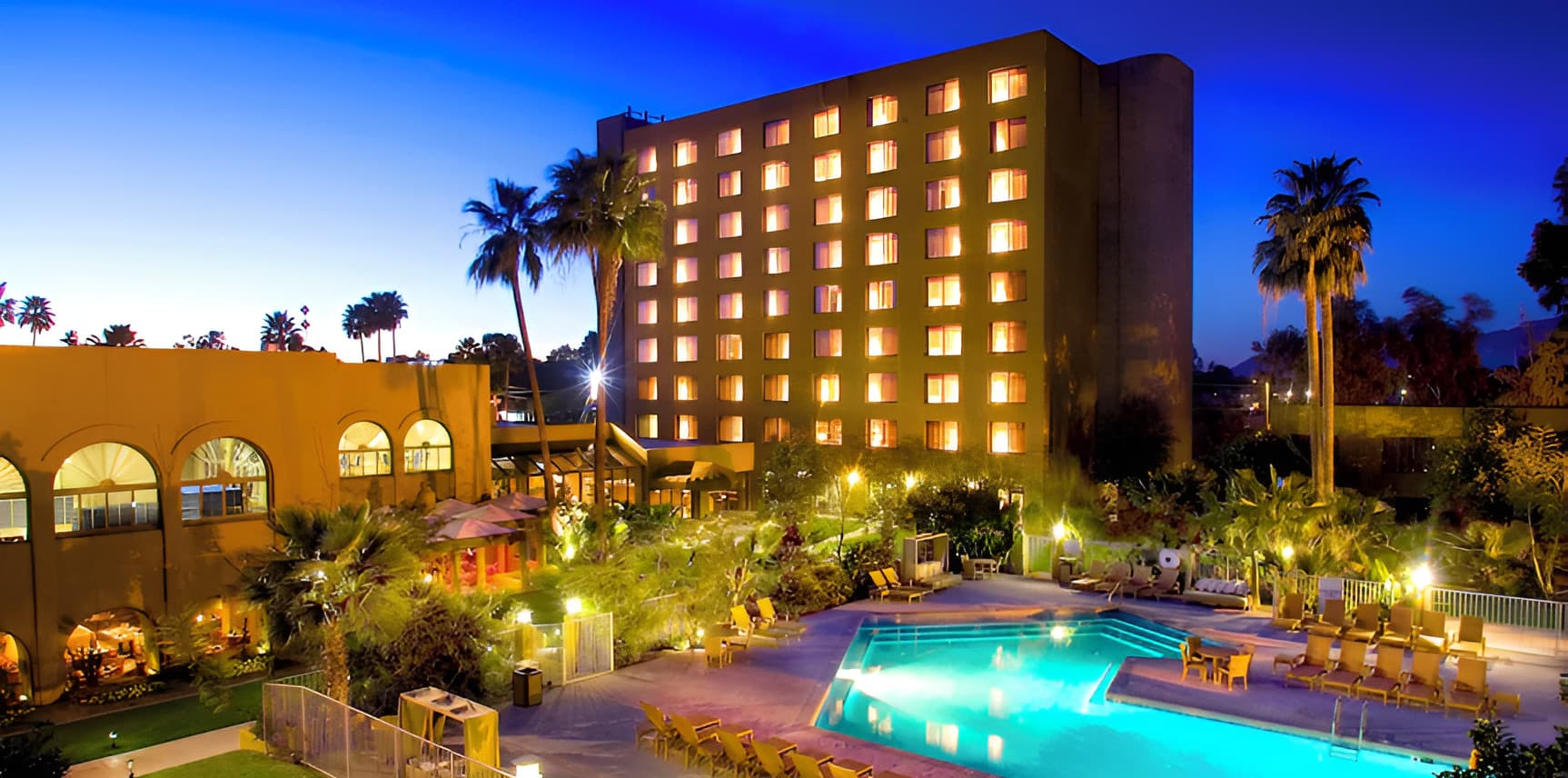 DoubleTree by Hilton Tucson Reid Park at dusk, the hotel tower and pool lit among palm trees